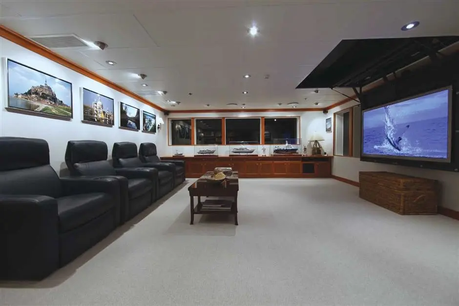 Sky lounge with a row of black leather recliners facing a screen lowered from the ceiling