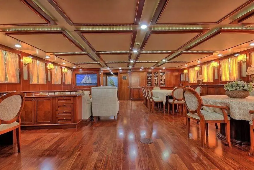 Main salon with mahogany panelling, a wooden floor, sofas and a dining table