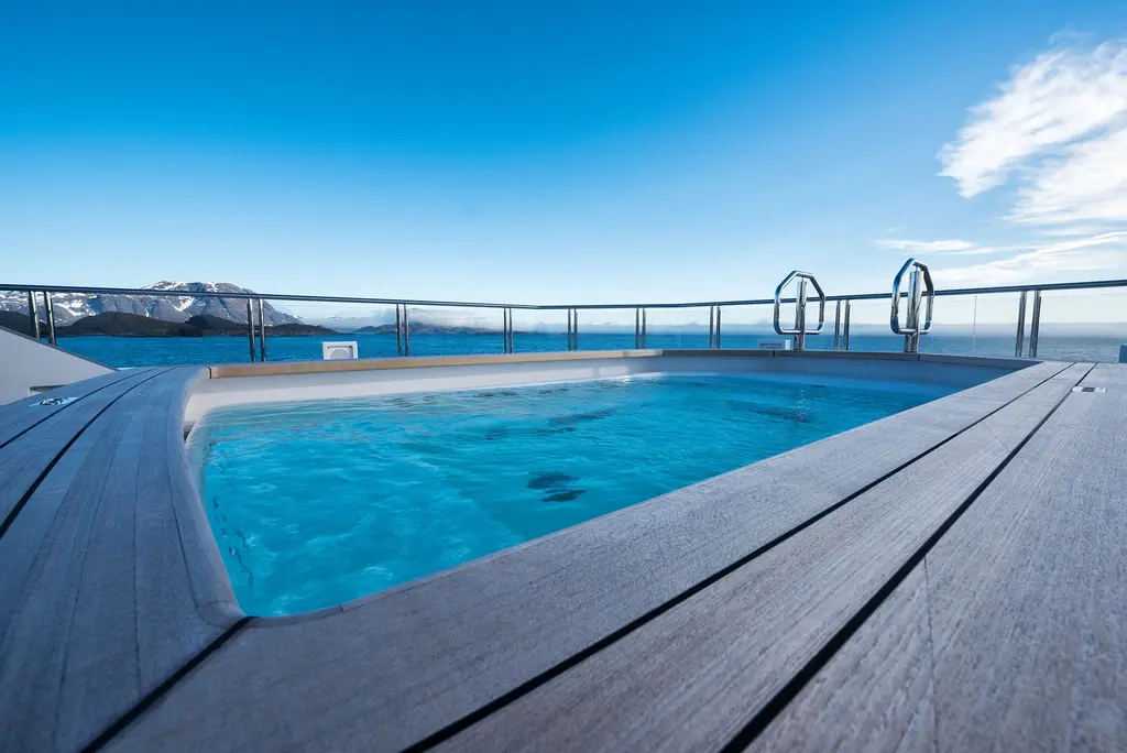 A deck pool with a teak surround, looking out over the sea under a blue sky
