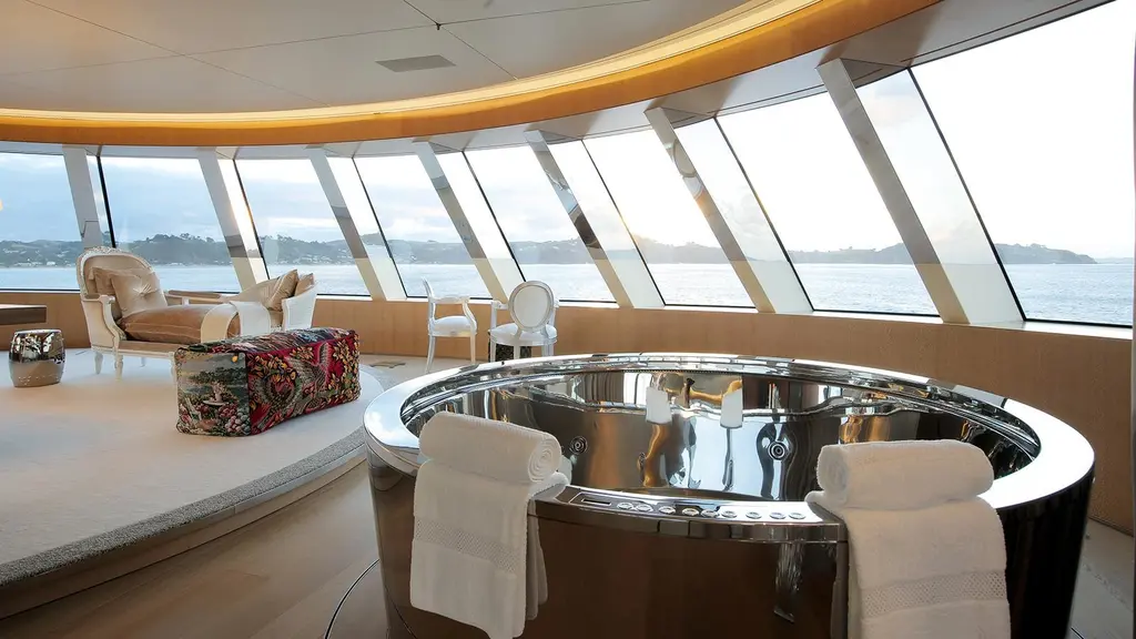 Round polished-steel tub under a curved band of windows looking out to sea