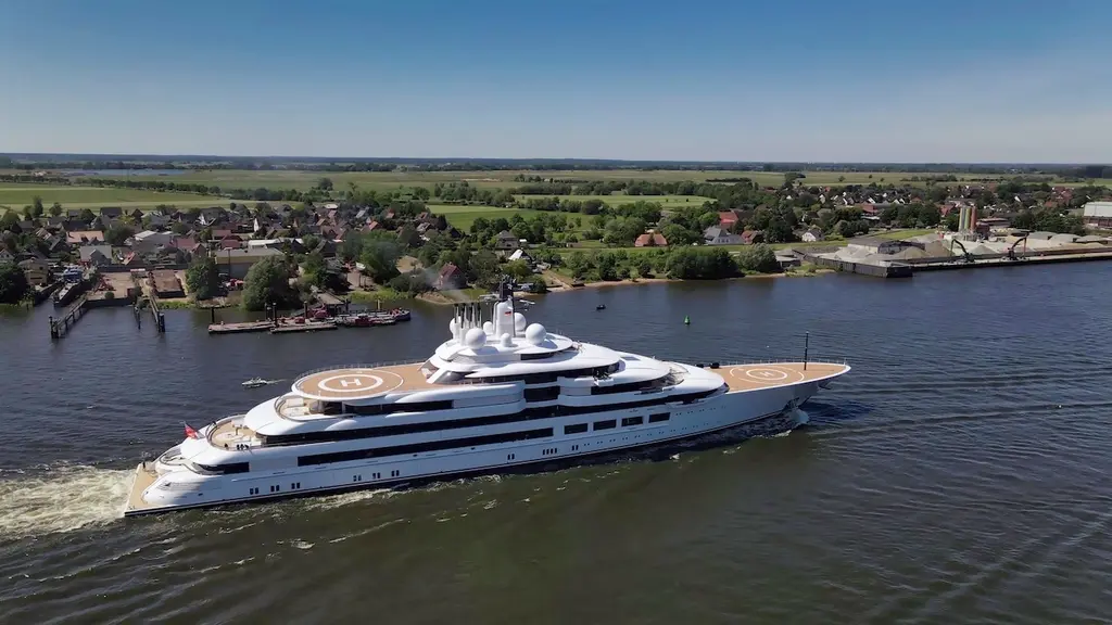 Aerial view of Scheherazade underway past a riverside village, both helipads visible