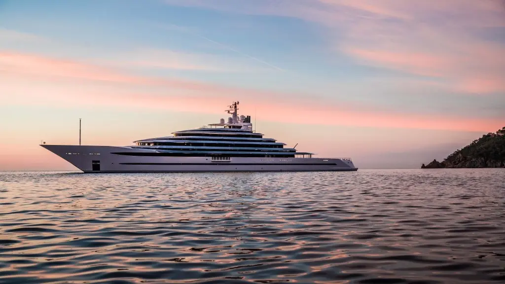 The yacht at anchor in profile under a pink evening sky