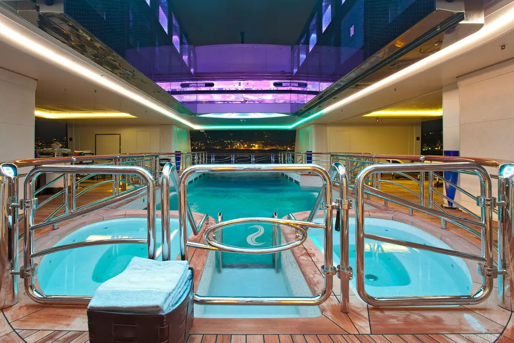 Indoor pool on Serene flanked by two round spa pools, lit in blue and violet