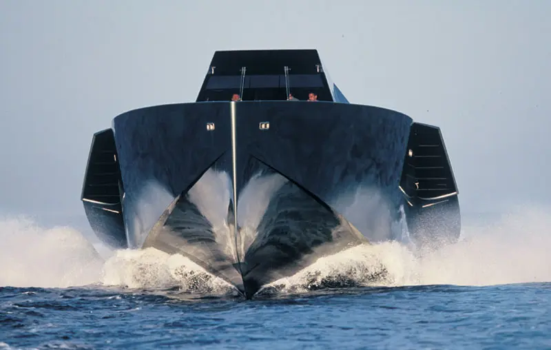 Head-on view of the Wallypower 118 at speed, spray from both sides of the dark hull