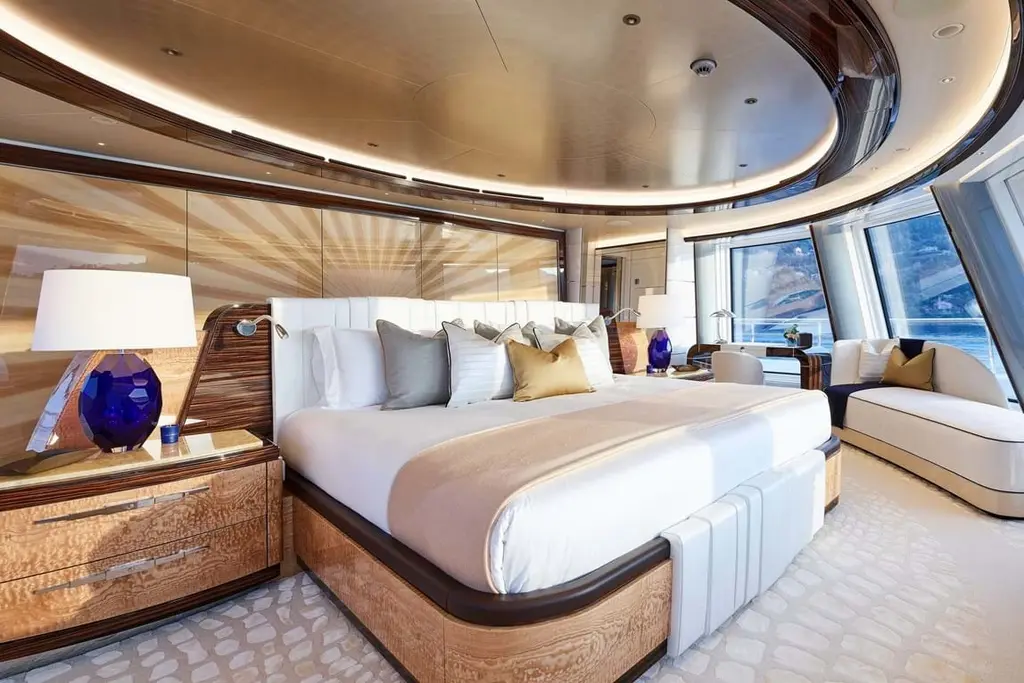 Owner’s cabin with a large double bed, burr-wood furniture and angled floor-to-ceiling windows