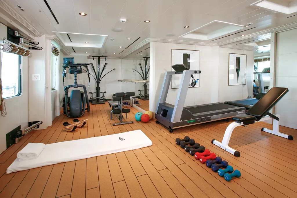 Gym with a treadmill, weight bench and dumbbells on a wooden floor