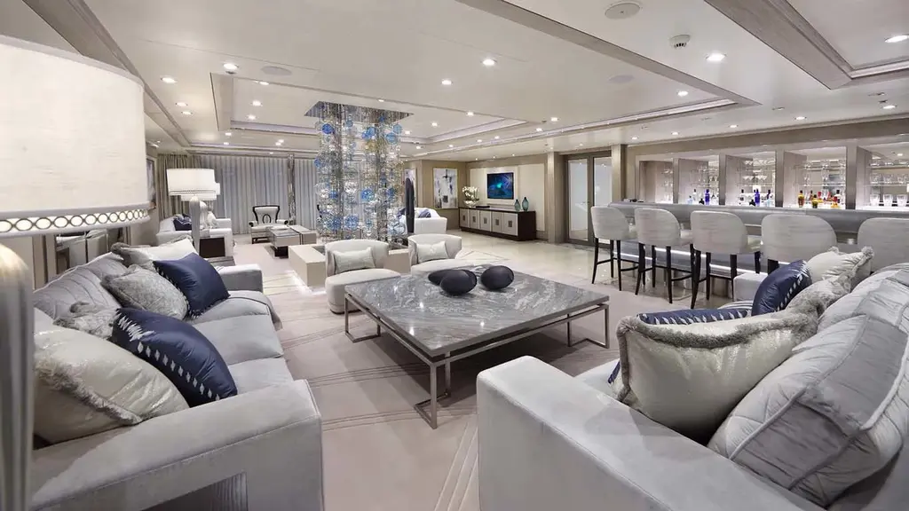 Main saloon with pale grey sofas, a stone coffee table and a bar with white stools
