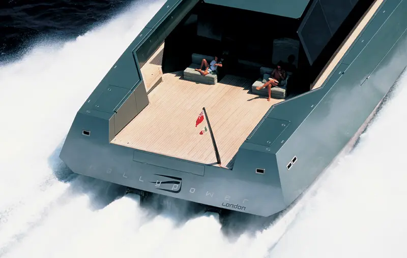 The Wallypower 118 from above and astern at speed, white wake behind the open aft deck