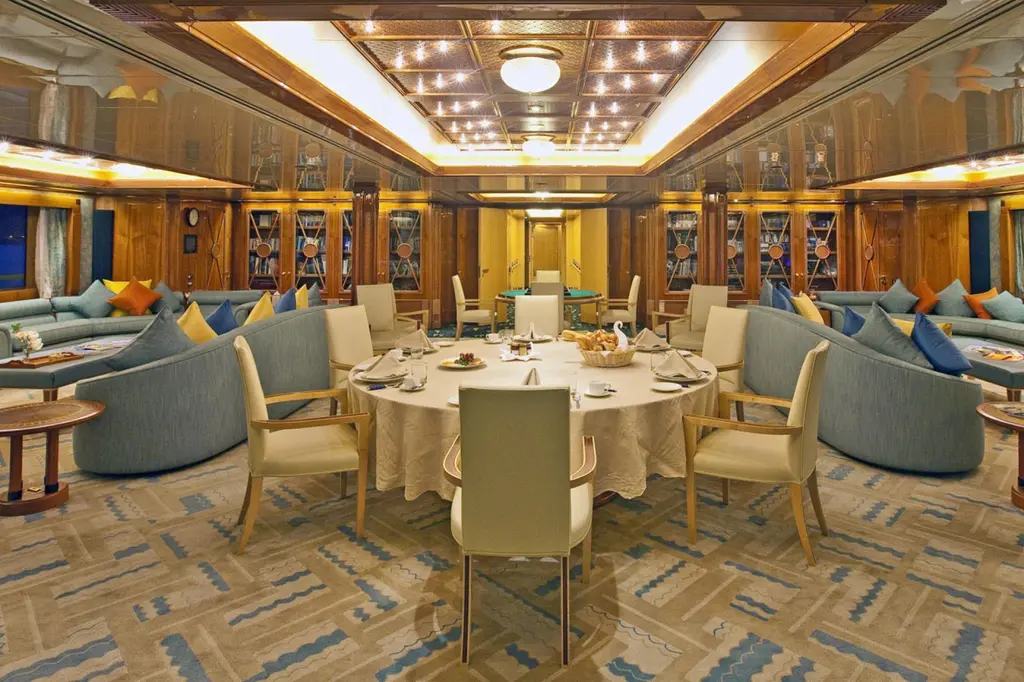 Lounge with blue-grey sofas, a round dining table and panelled wood walls