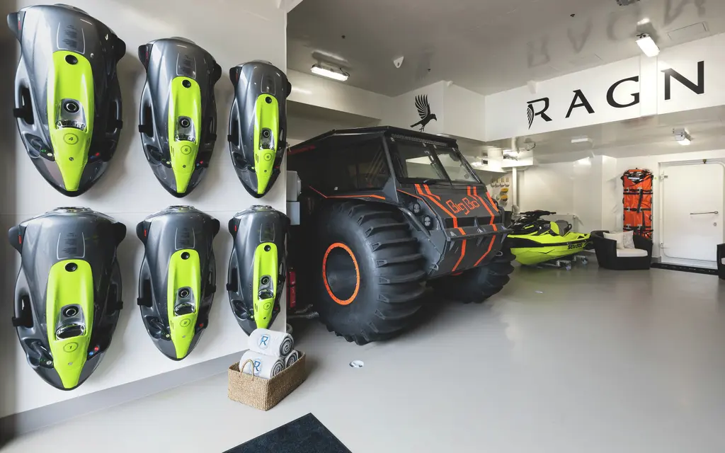 The garage with six Seabobs on a wall rack, a large-tyred amphibious vehicle and a jet ski, with RAGNAR painted on the wall