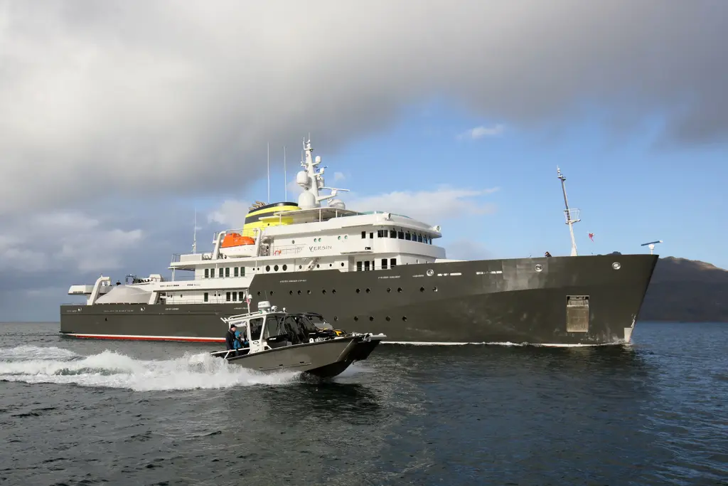 A grey tender running fast past Yersin's starboard side in choppy water