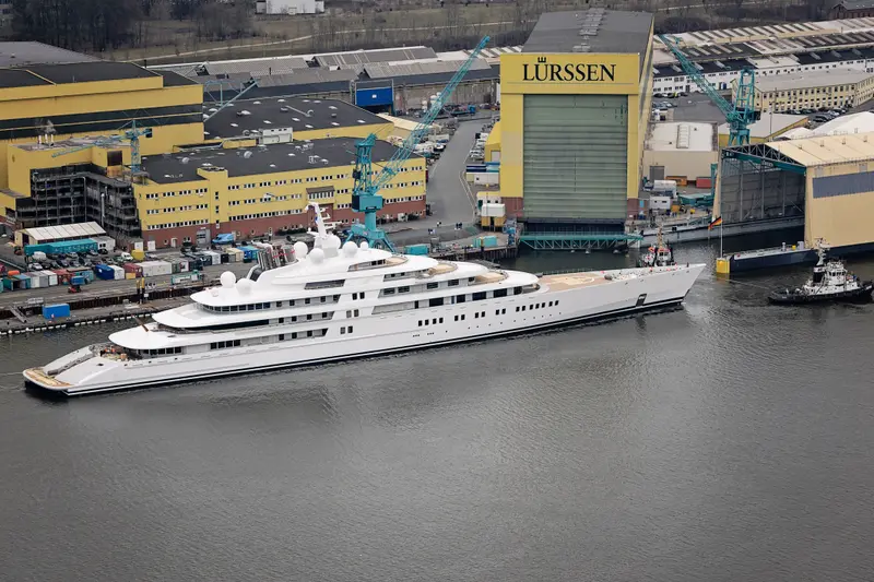 Azzam afloat beside the Lürssen shipyard, seen from the air at a three-quarter angle