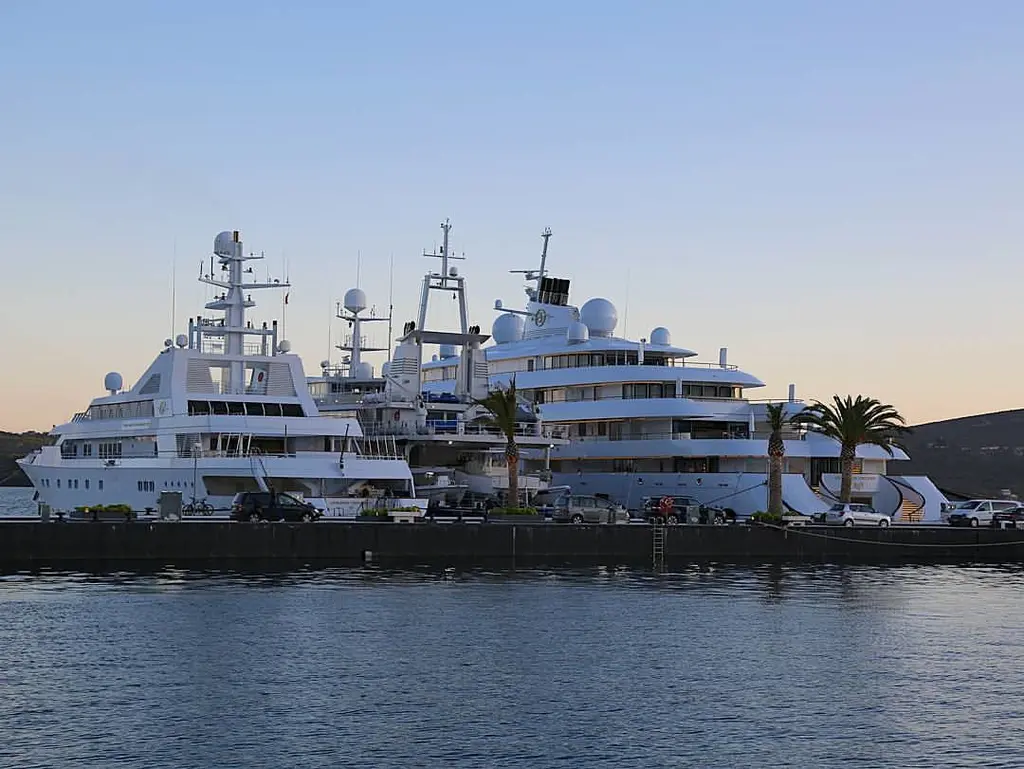 Golden Odyssey moored beside other large yachts at a quay at dusk