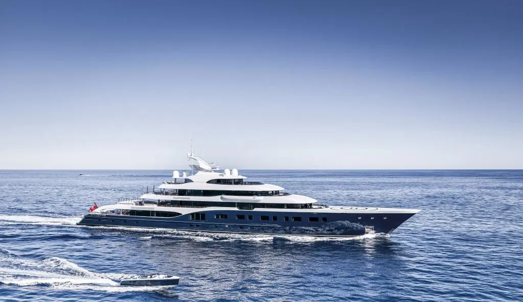 Symphony in starboard profile on open water, a tender running alongside
