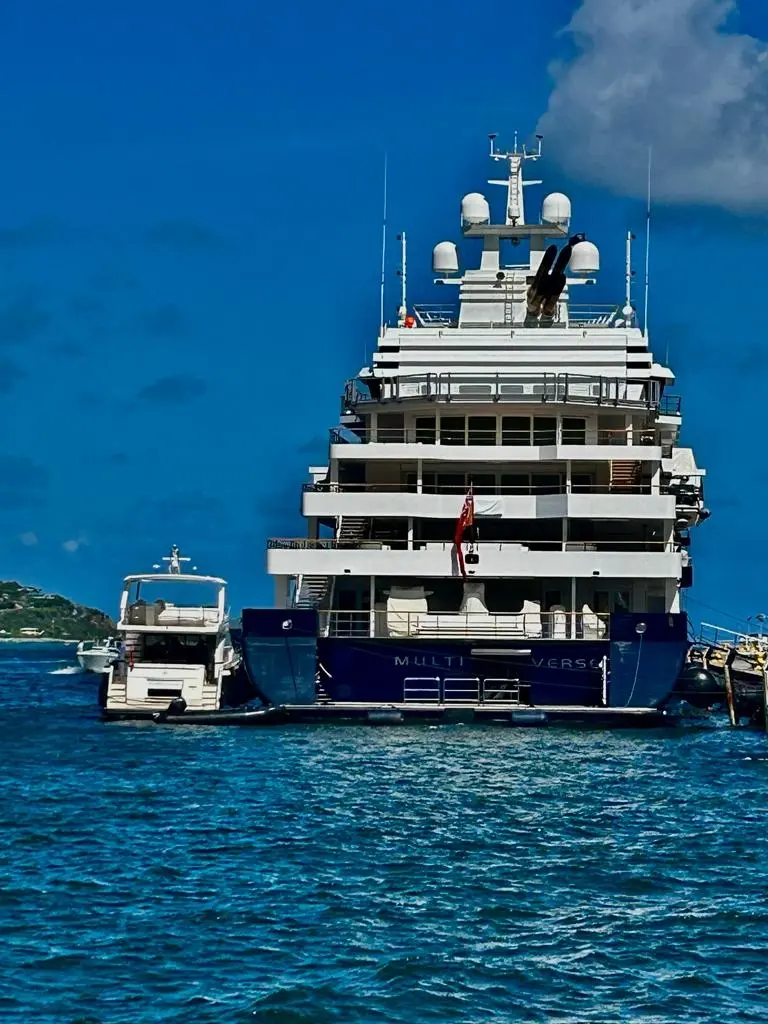 Stern of Multiverse with her name on the transom and a motor yacht tender alongside