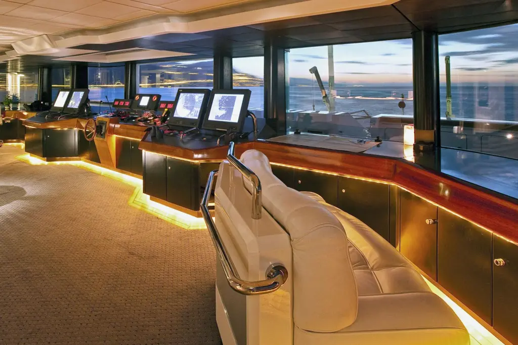 Wheelhouse with navigation screens and a helm chair, sea view through the windows