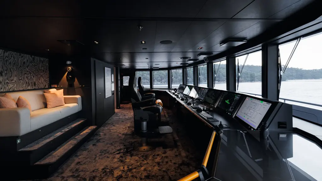 Nebula's bridge with a long dark console of screens and two helm chairs along the forward windows, and a grey sofa on a raised step to the left