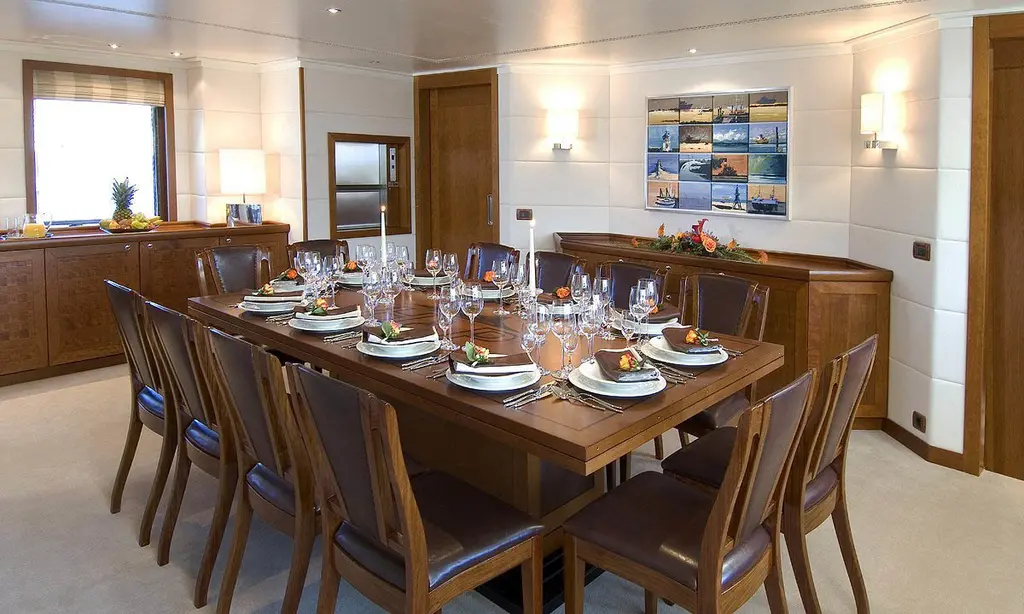 Dining room with a long wooden table laid for ten and dark wood sideboards, before the 2021 refit