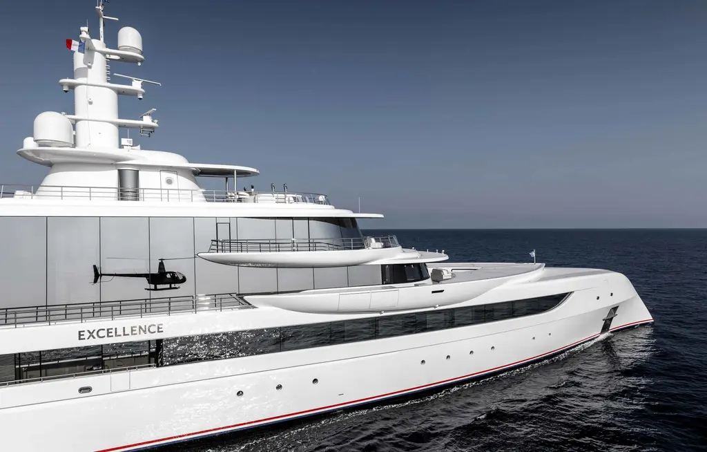 Close view of the forward superstructure and mast of Excellence, her name on the hull side and a helicopter in front of the glass