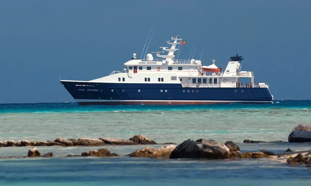 Hanse Explorer in profile off a rocky shore in clear turquoise water