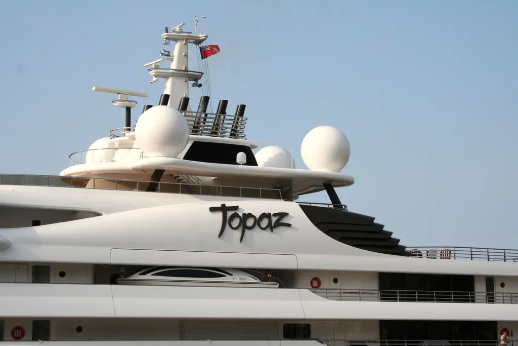 Close-up of the upper decks: the Topaz nameplate, white radar domes, black exhaust stacks and the mast with a red ensign