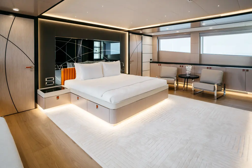 Owner's stateroom with a large bed, a pale carpet, armchairs and wide hull windows
