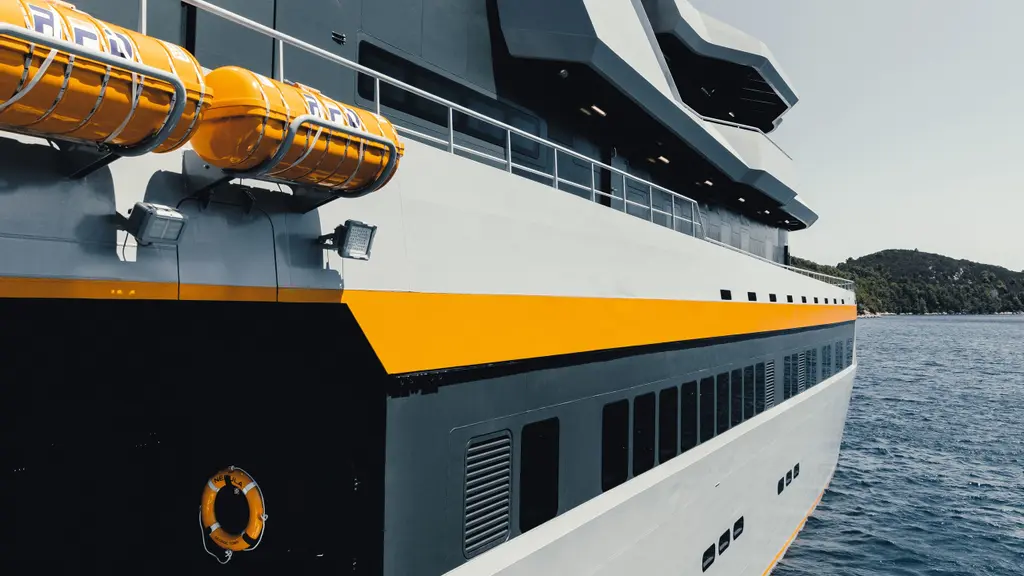 Close view along Nebula's starboard side at anchor: orange life-raft canisters on the upper deck, the orange stripe and rows of windows in the grey hull