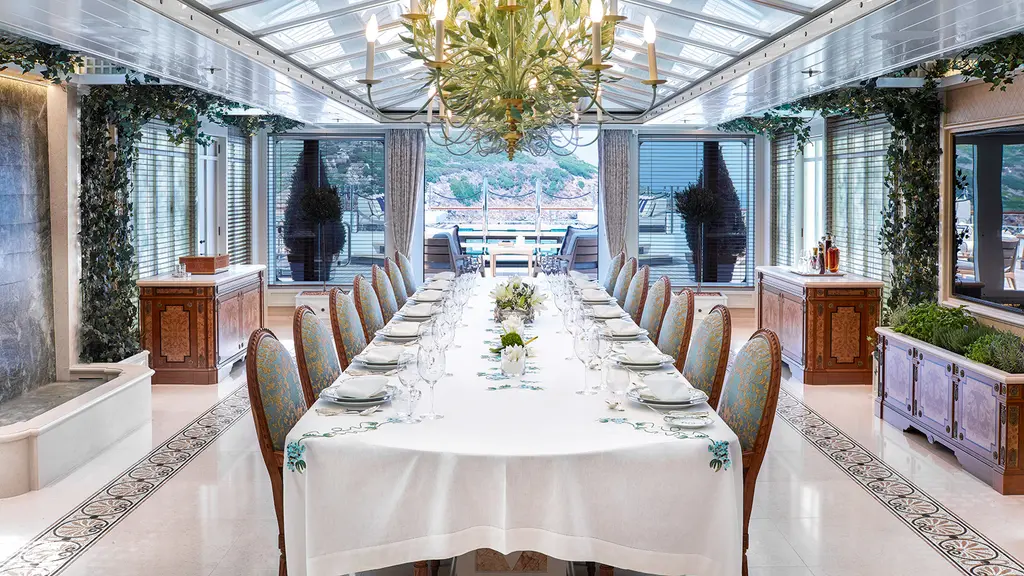 Long dining table under a glass roof in the sun deck winter garden