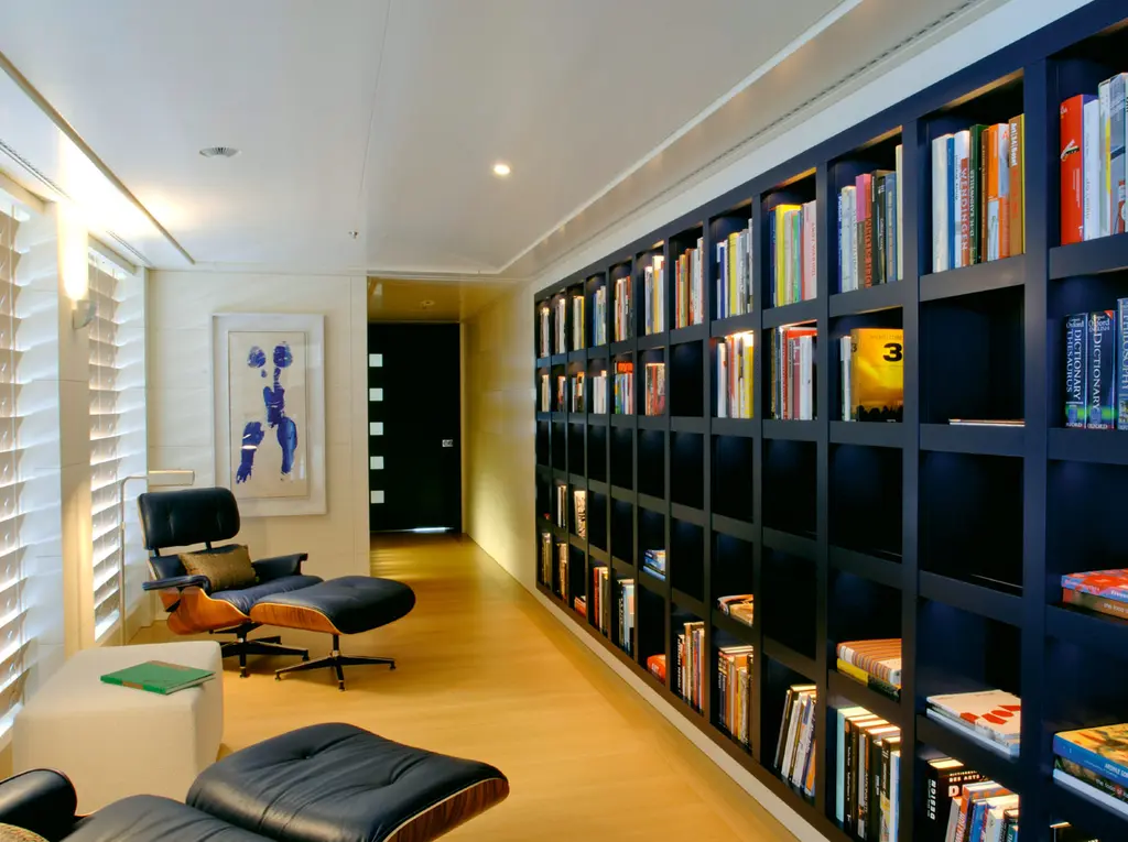 A reading corner with a leather lounge chair and a wall of books in black shelving