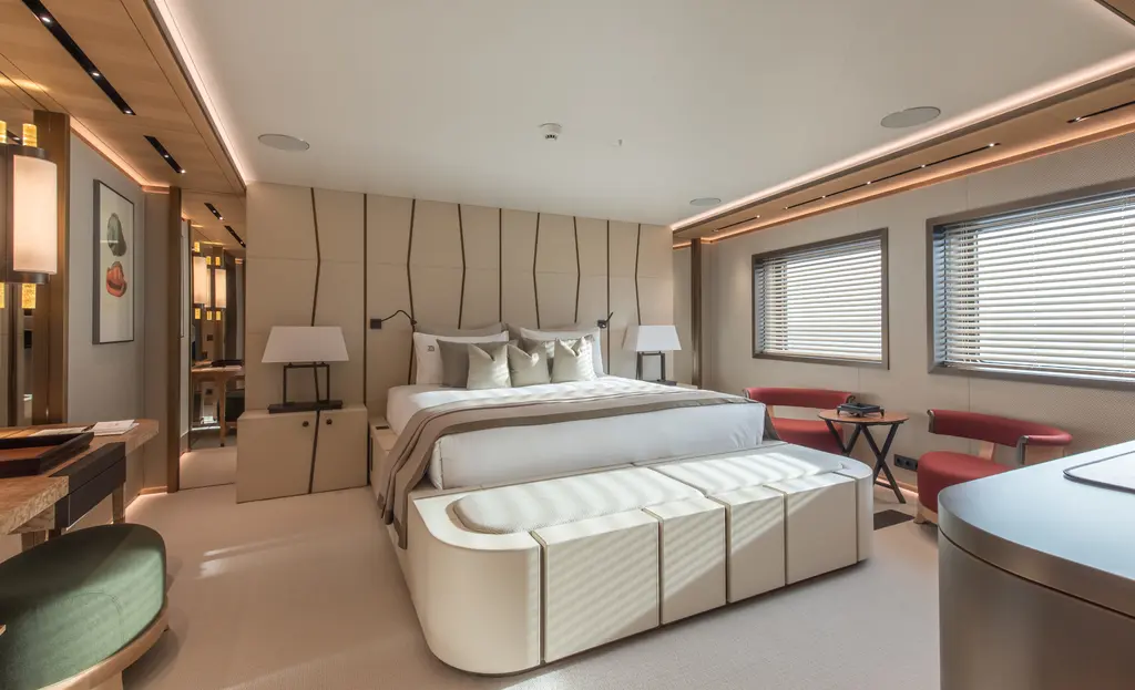 Guest cabin with a double bed, padded bench at the foot and two windows with blinds