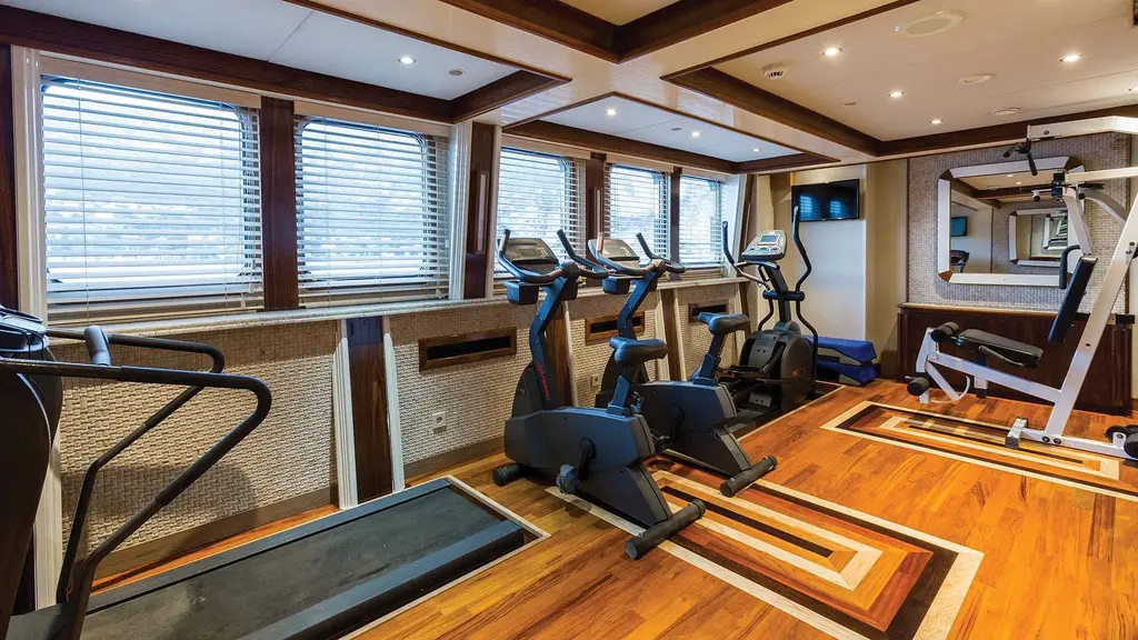 Gym with an inset treadmill, exercise bikes and weight machines on a wooden floor