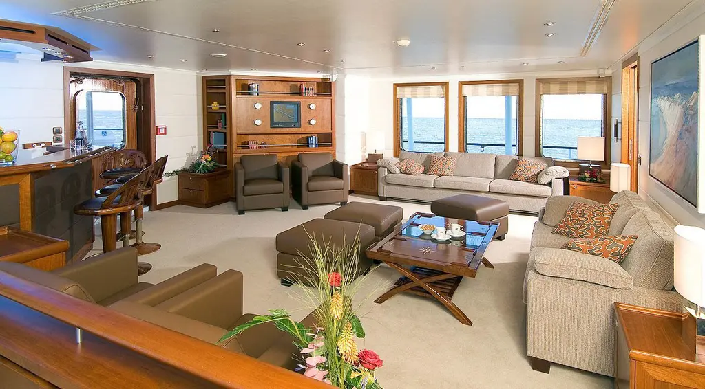 Main saloon with beige sofas, wood panelling and a row of square windows, as fitted before the 2021 refit