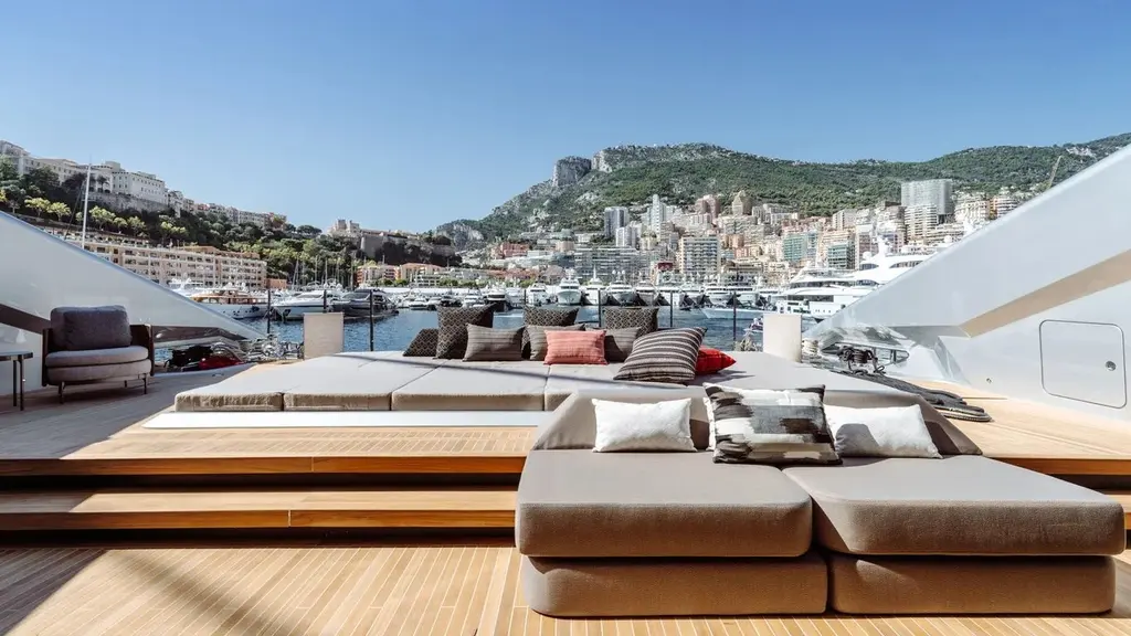 Teak deck with grey sunpads and cushions, Monaco harbour and hillside behind