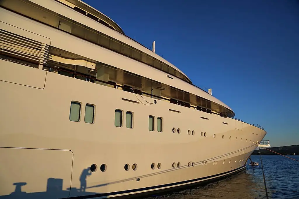 Golden Odyssey's hull and superstructure seen from the quay towards the bow, in low evening light