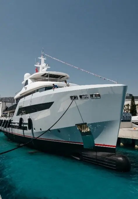 Heeus moored at a quay in 2022, before delivery, with a line of flags from the mast to the bow, seen from the starboard bow