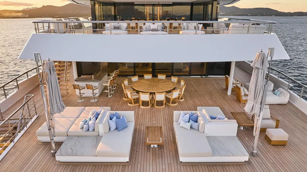 Aft deck with a round teak table, white sofas and a bar under the deck above