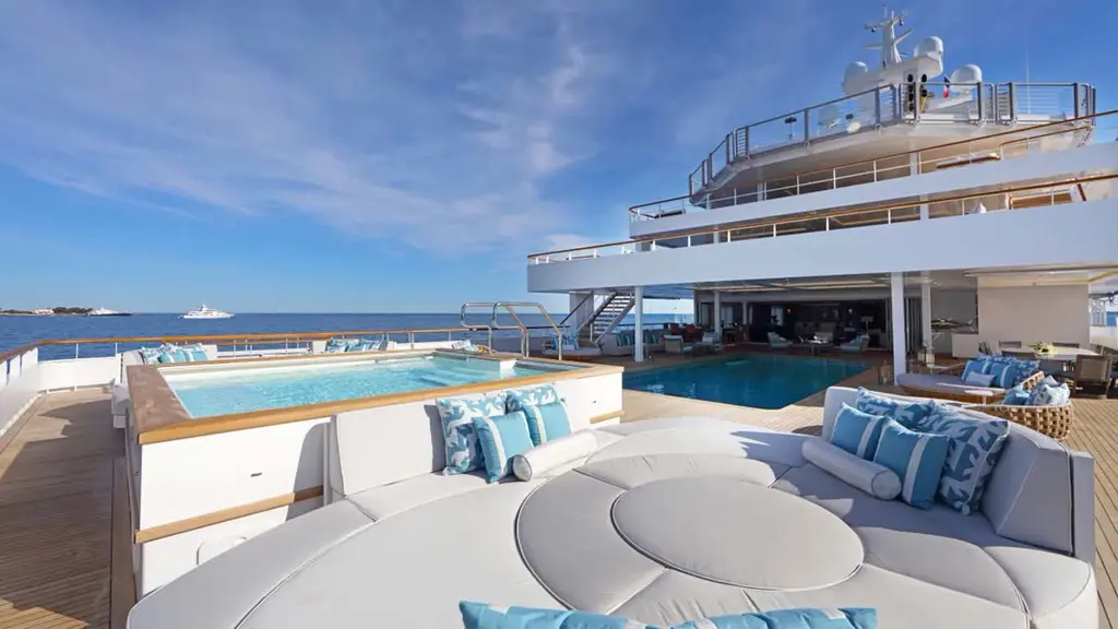 Aft deck of Andromeda with a large sunpad, a raised spa pool and the swimming pool behind it