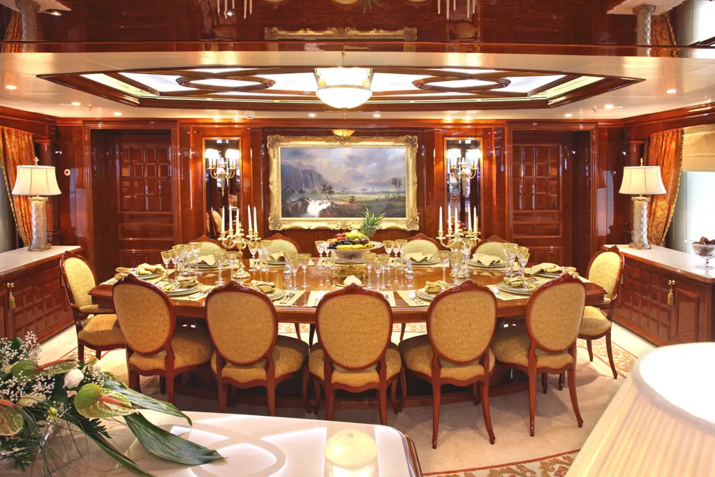 Formal dining room with a long table, upholstered chairs and a landscape painting