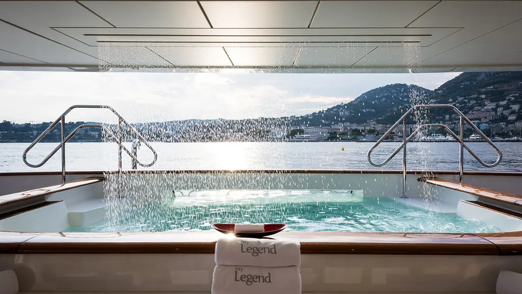 The spa pool on Legend's aft deck, filled by a waterfall from the deck above, with a coastline beyond