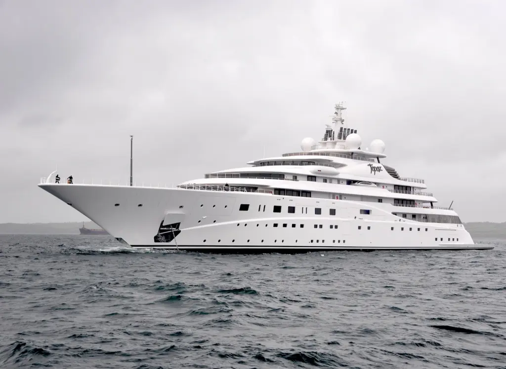 The yacht under way on a grey day, seen from the bow quarter, with crew on the foredeck