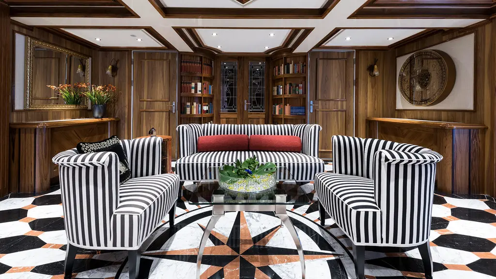 Wood-panelled lobby with striped armchairs and sofa on a black-and-white floor centred on a compass star