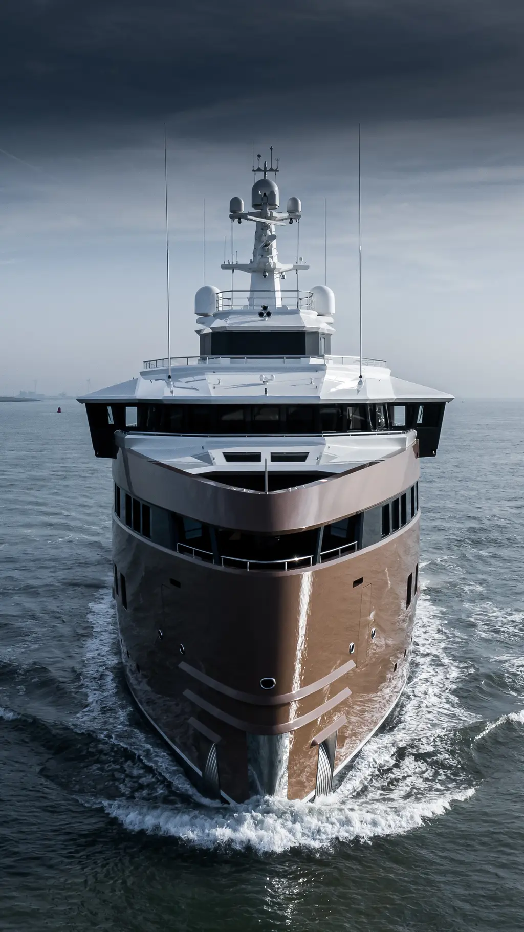 La Datcha approaching head-on under a grey sky, showing her tall vertical bow and the enclosed bridge