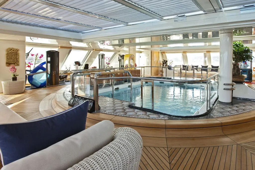 Indoor pool under a louvred roof, enclosed in glass with a teak surround and columns