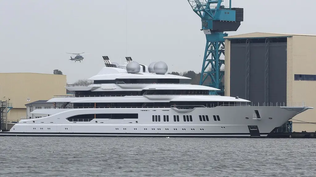 Amadea alongside at a shipyard with a helicopter above and a crane behind