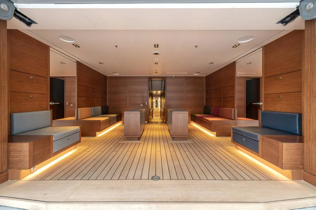 Boot room with wooden lockers, leather benches and a teak floor, opening onto the beach club