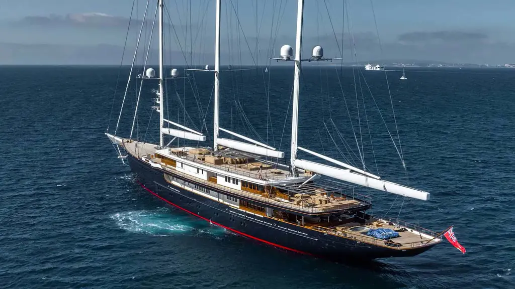 Aerial view of Koru from the stern quarter, showing teak decks, the aft pool and the booms of all three masts