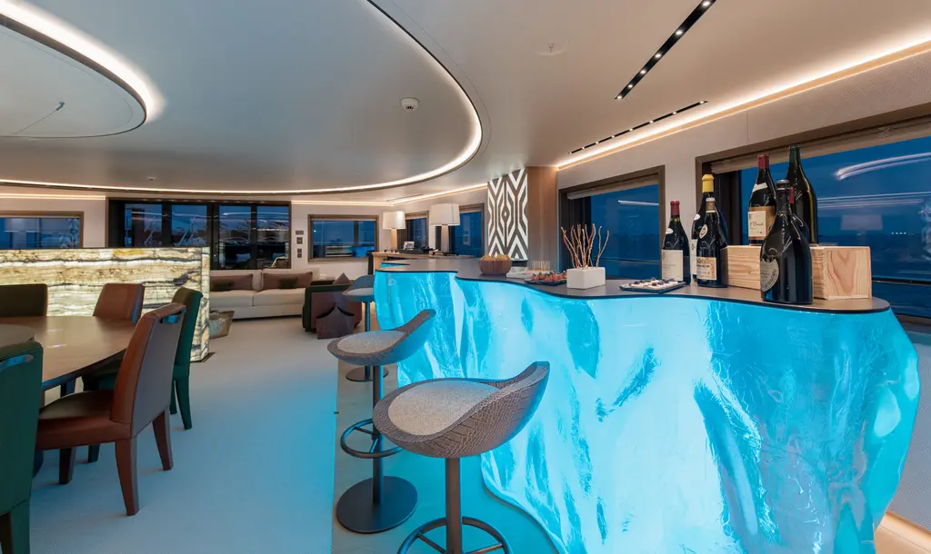 Bar with a glowing blue sculpted counter shaped like ice, bar stools and a wine display