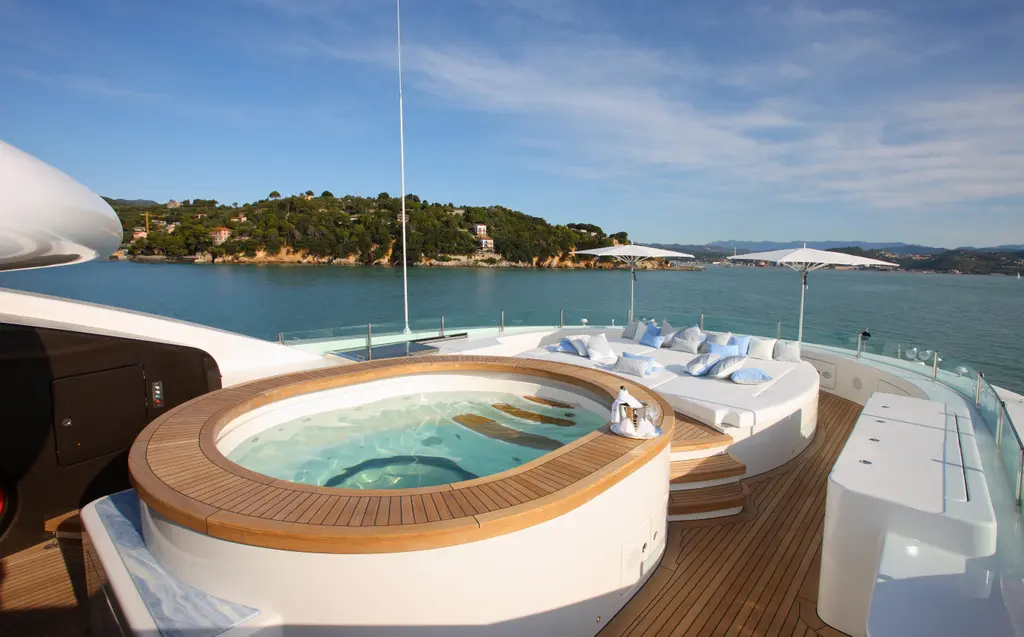 Round spa pool with a teak surround on the sun deck, sun pads behind
