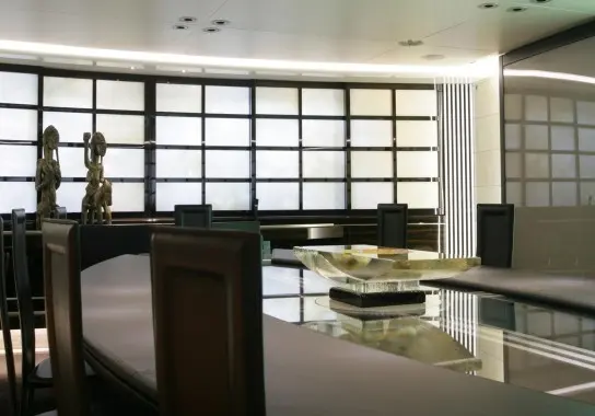 Dining room with dark wooden chairs, a glass table and backlit screen panels