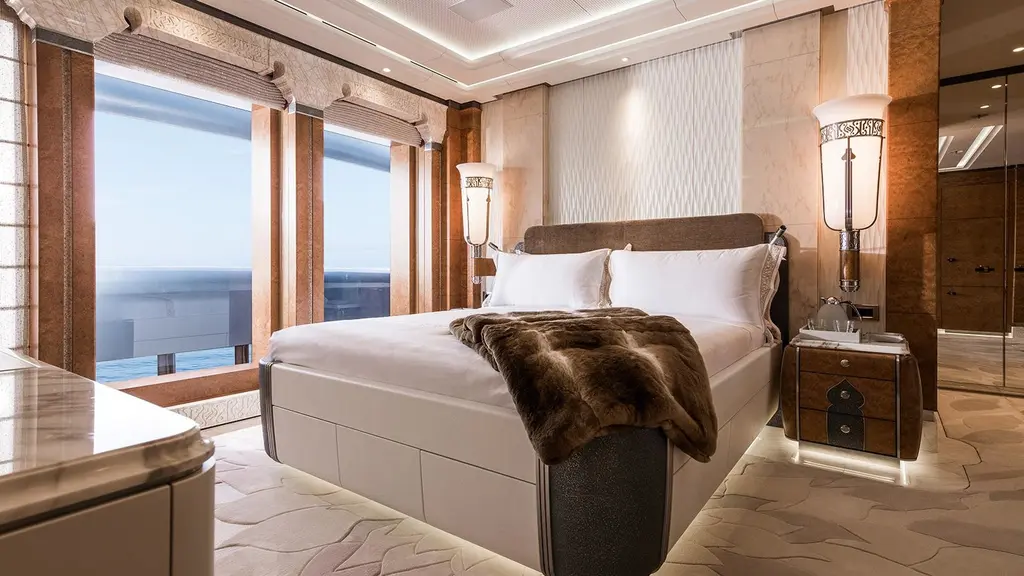 A guest stateroom with a double bed, wall lamps and full-height windows